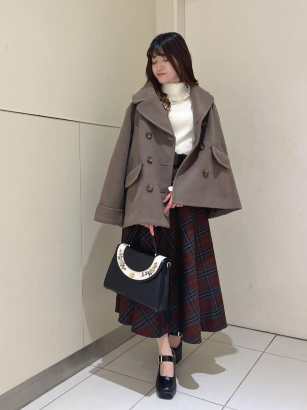 ブラック系のパンプス、ブラック系のハンドバッグ、ブラック系のスカートを着用したレディースの冬コーディネートの2枚目の写真