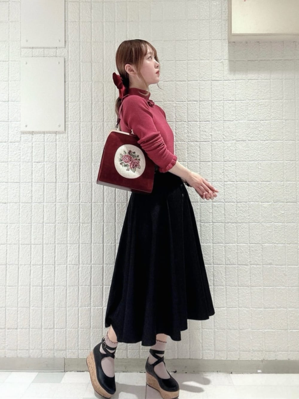 ブラック系のパンプス、ブラック系のデニムスカート、レッド系のハンドバッグを着用したレディースの冬コーディネートの2枚目の写真