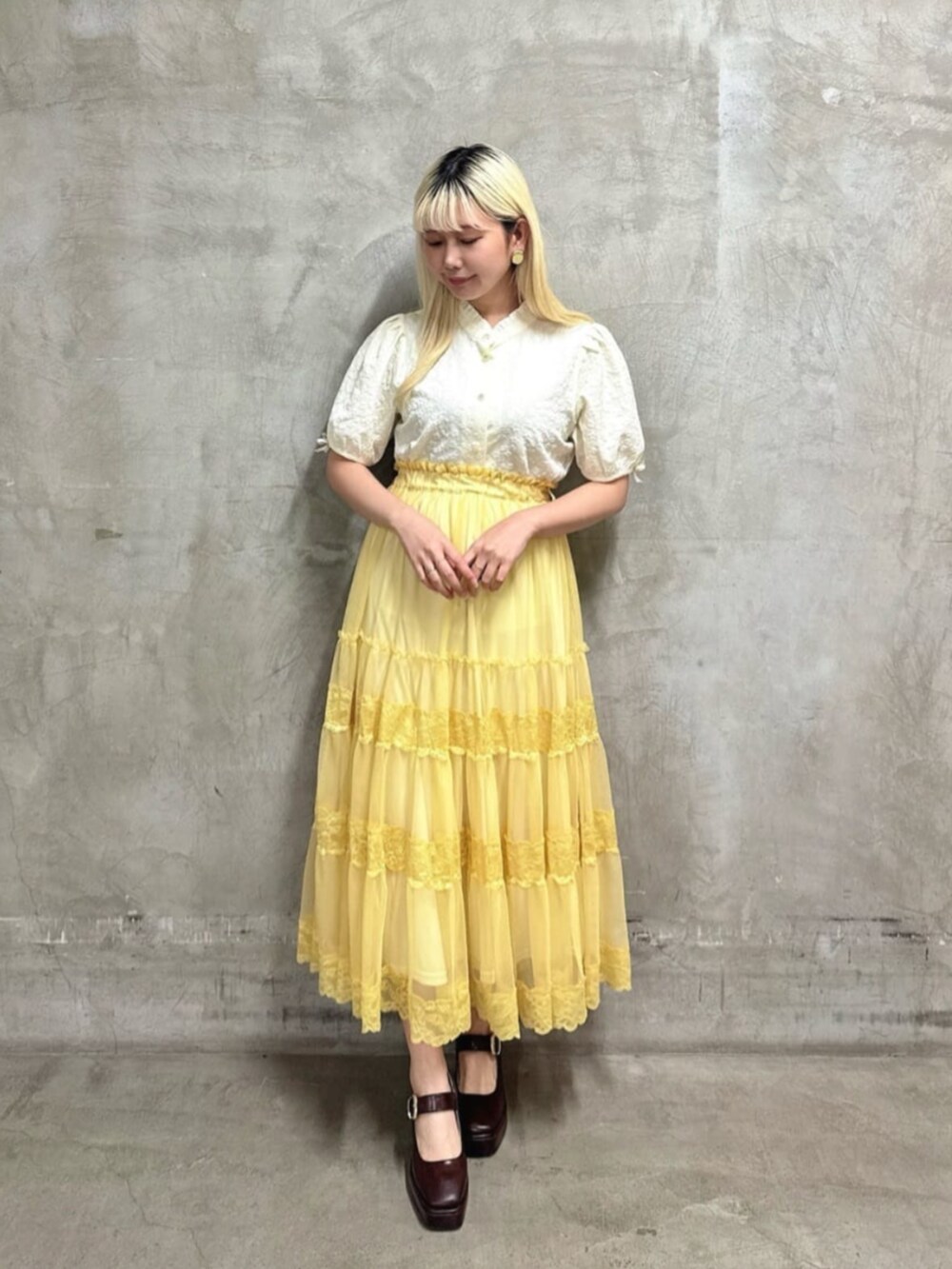 ブラウン系のパンプス、イエロー系のスカート、ホワイト系のシャツ/ブラウスを着用したレディースの夏コーディネートの2枚目の写真