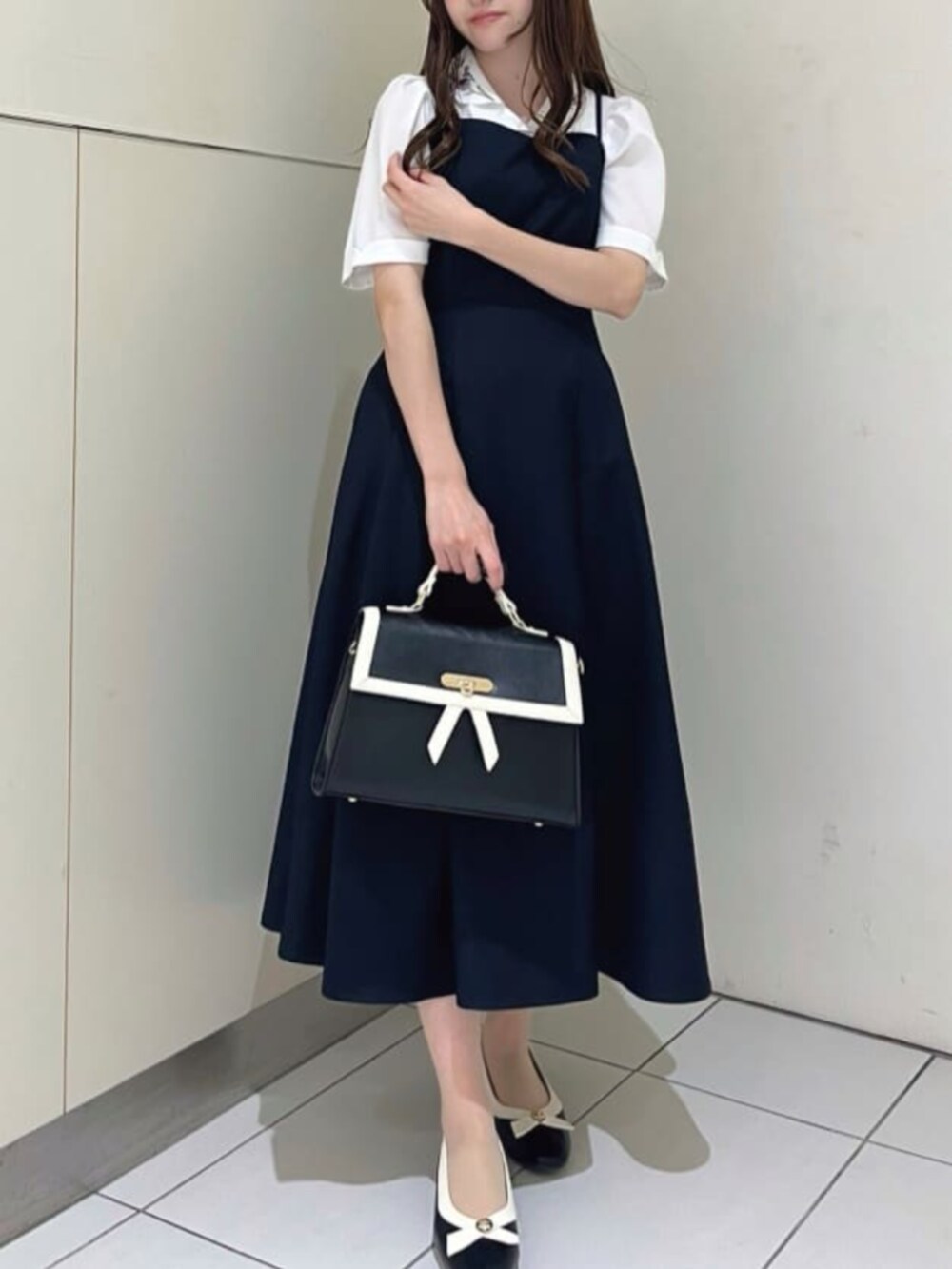 ブラック系のハンドバッグ、ブルー系のワンピース、ブラック系のパンプスを着用したレディースの春コーディネートの2枚目の写真