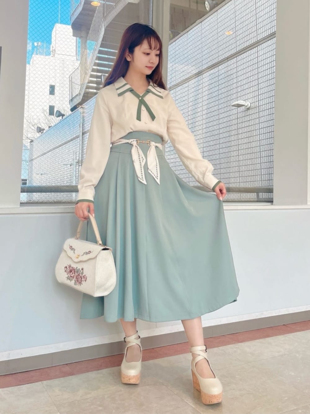 ホワイト系のハンドバッグ、ホワイト系のシャツ/ブラウス、グリーン系のスカートを着用したレディースの冬コーディネートの2枚目の写真