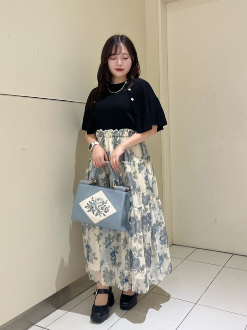 ブラック系のパンプス、ブルー系のトートバッグ、ブルー系のスカートを着用したレディースの秋コーディネートの2枚目の写真