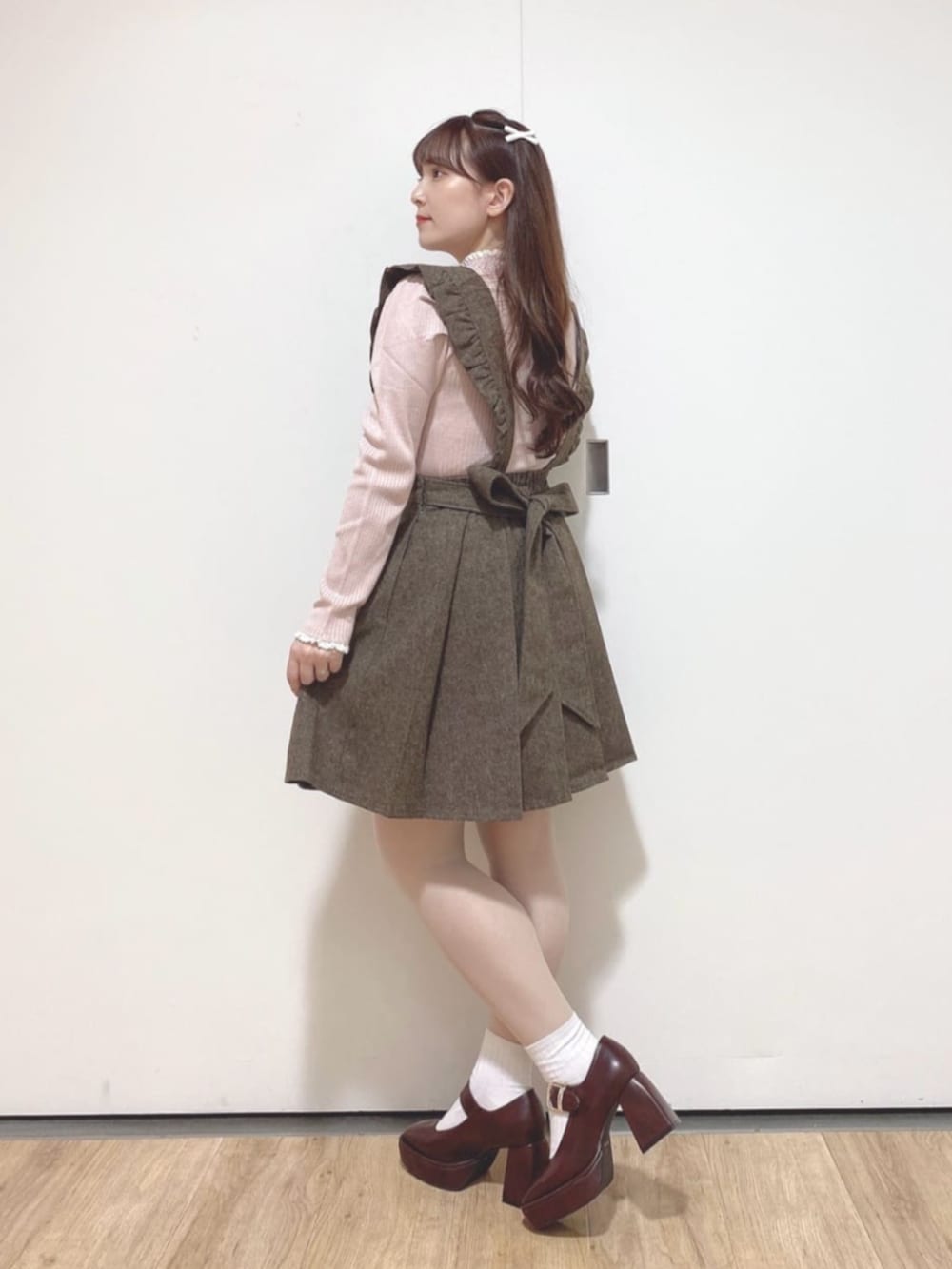 ブラウン系のパンプス、ブラウン系のジャンパースカート、ピンク系のニット/セーターを着用したレディースの秋コーディネートの2枚目の写真