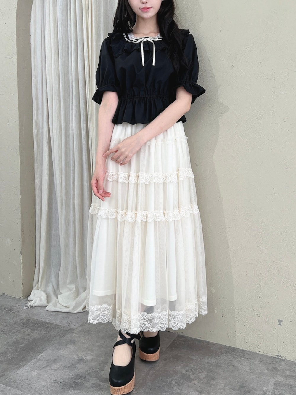 ブラック系のパンプス、ホワイト系のスカート、ブラック系のシャツ/ブラウスを着用したレディースの夏コーディネートの3枚目の写真