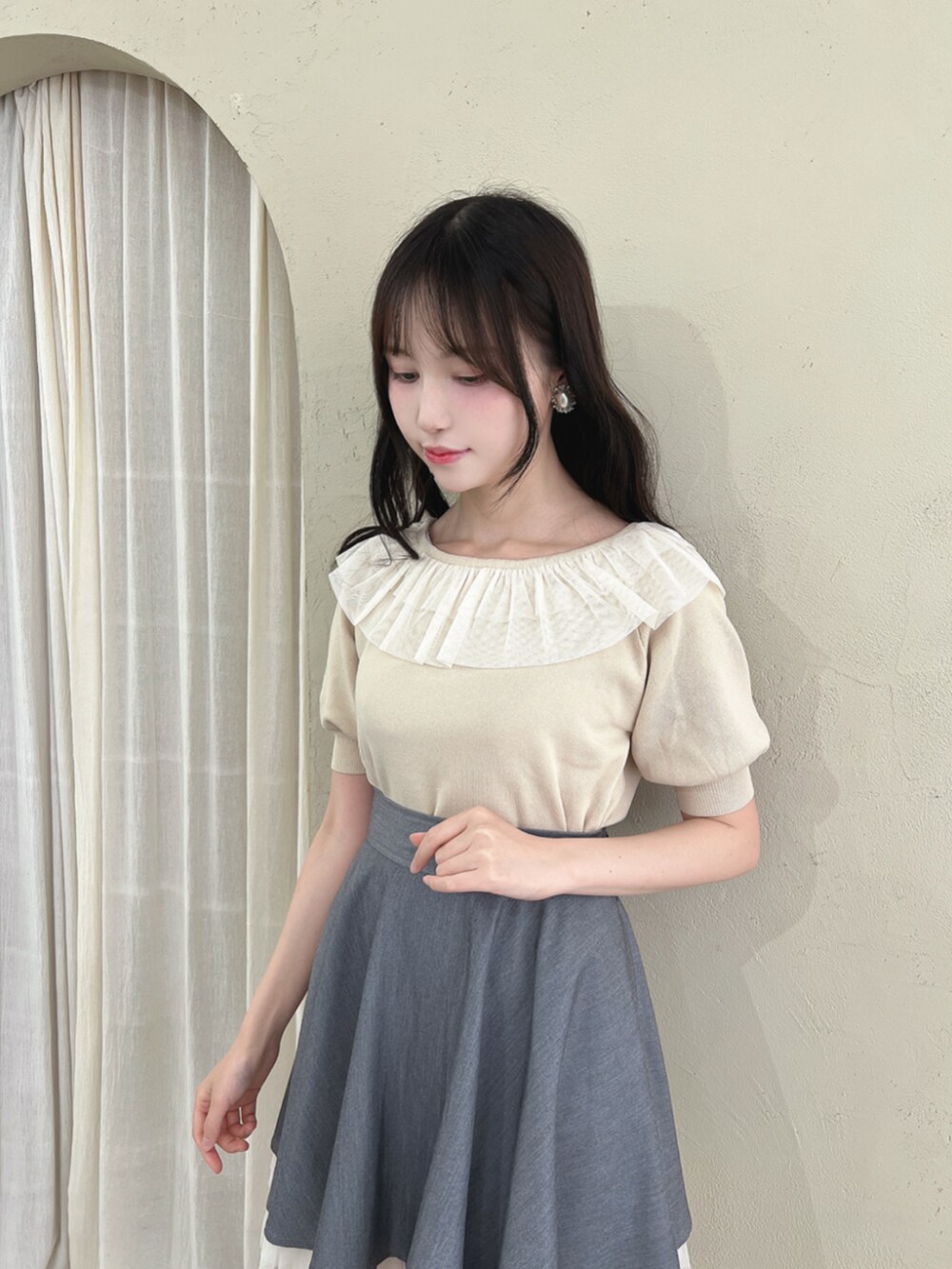 ブラック系のパンプス、グレー系のスカート、ホワイト系のニット/セーターを着用したレディースの夏コーディネートの2枚目の写真