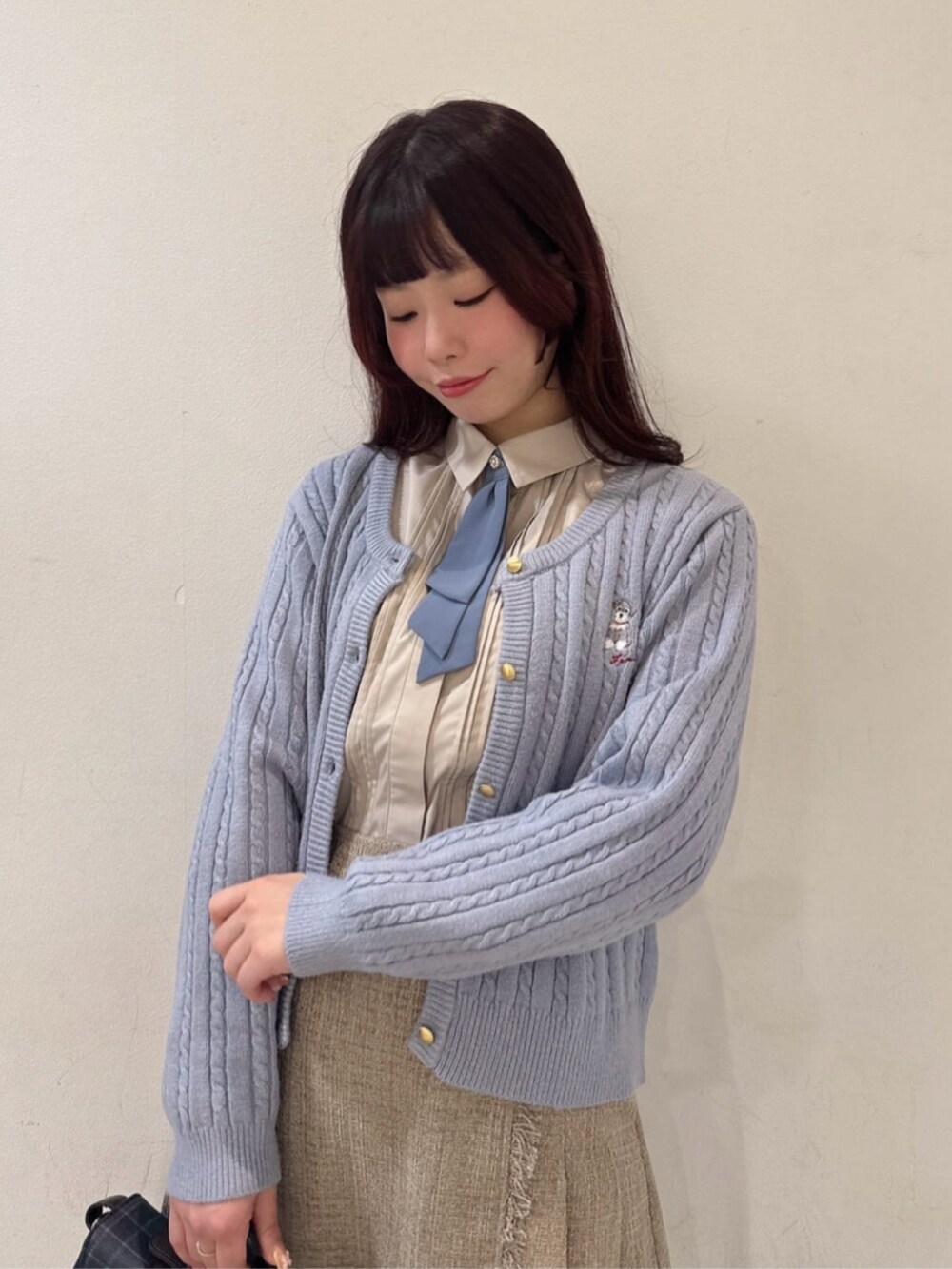 ブルー系のショルダーバッグ、グレー系のカーディガン/ボレロ、ベージュ系のスカートを着用したレディースの秋コーディネートの2枚目の写真