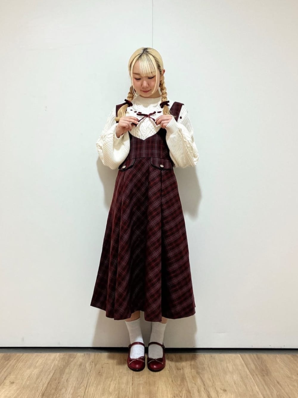 レッド系のバレエシューズ、ホワイト系のニット/セーター、レッド系のジャンパースカートを着用したレディースの冬コーディネートの2枚目の写真