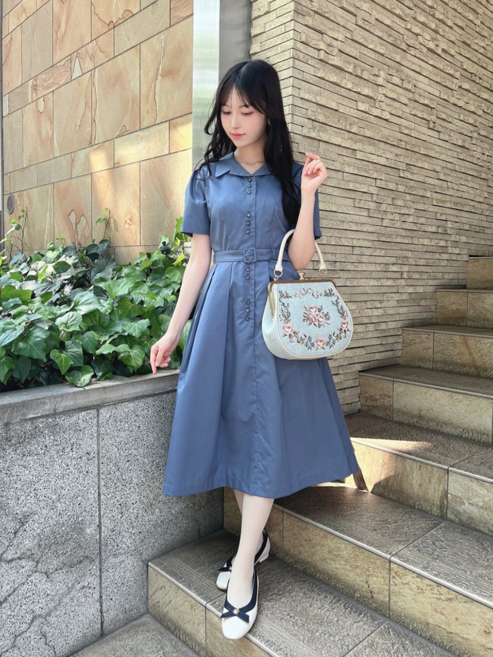 ホワイト系のパンプス、ホワイト系のハンドバッグ、ブルー系のシャツワンピースを着用したレディースの夏コーディネートの3枚目の写真