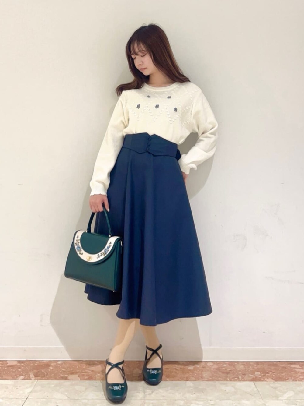 ブルー系のハンドバッグ、ブルー系のパンプス、ホワイト系のニット/セーターを着用したレディースの冬コーディネートの2枚目の写真
