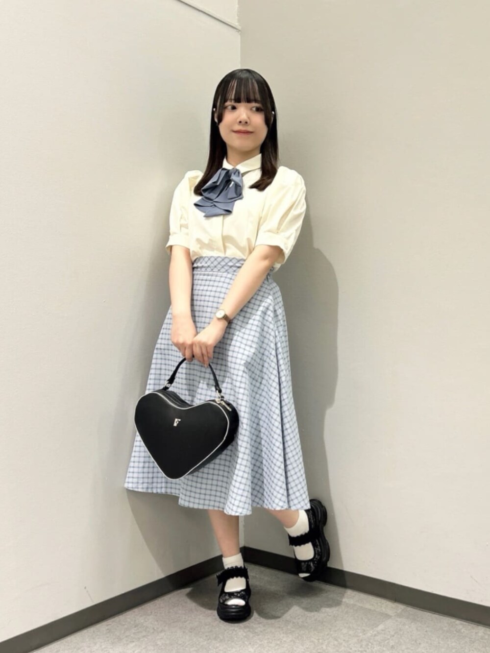 ブルー系のスカート、ブラック系のハンドバッグ、ホワイト系のシャツ/ブラウスを着用したレディースの夏コーディネートの3枚目の写真