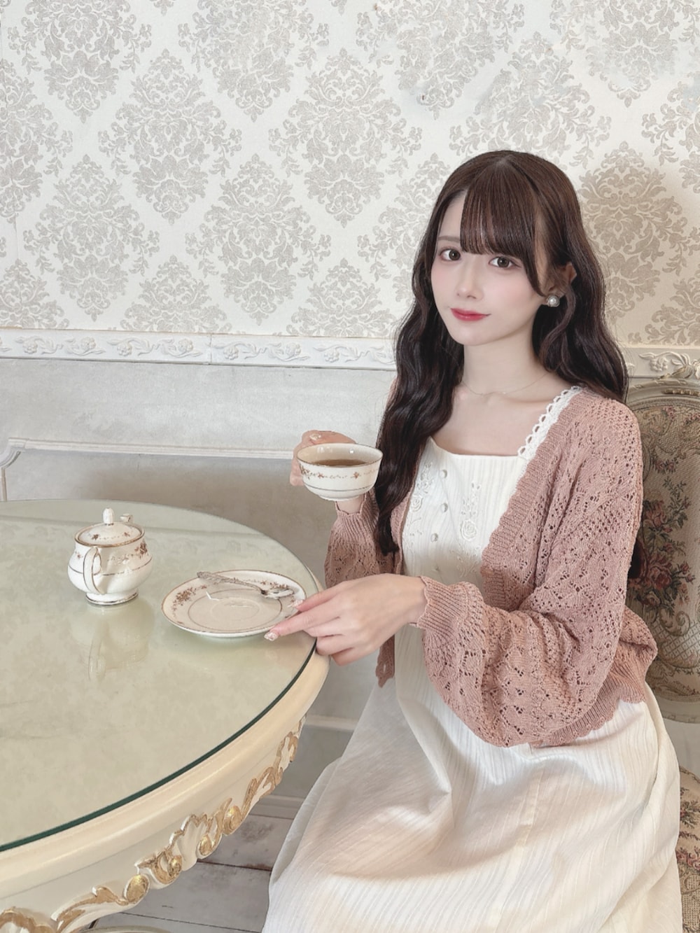 ホワイト系のワンピース、ピンク系のカーディガン/ボレロを着用したレディースの春コーディネートの2枚目の写真