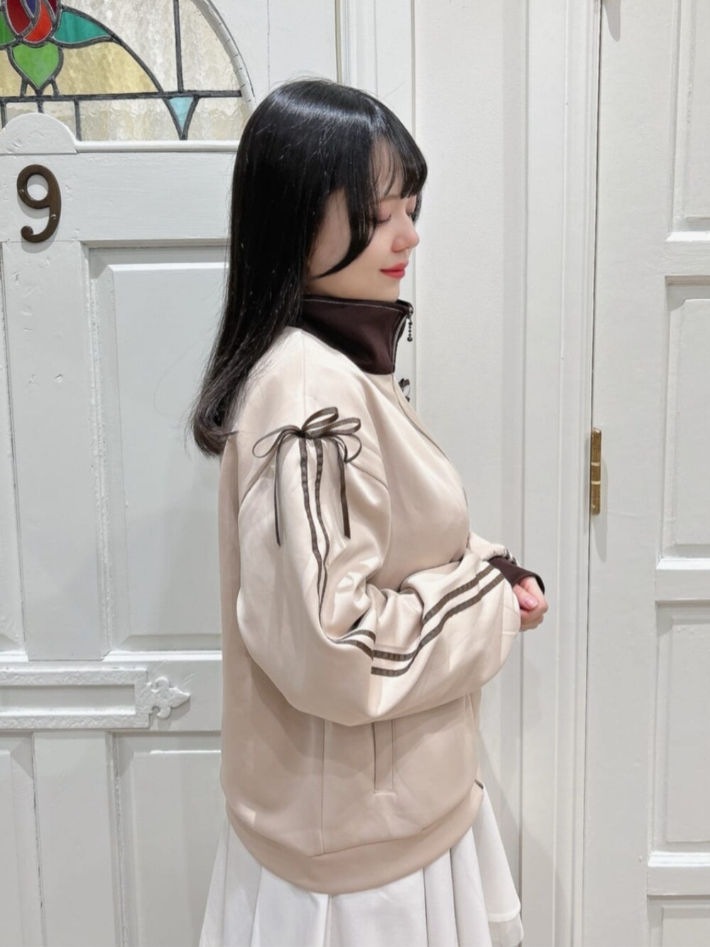 ホワイト系のスカート、ベージュ系のブルゾン、ブラウン系のブーツを着用したレディースの冬コーディネートの2枚目の写真