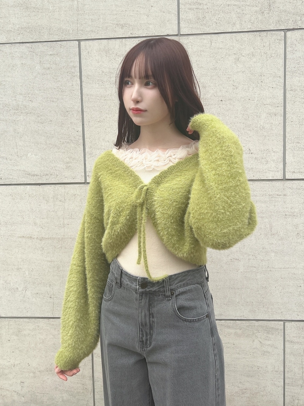 グレー系のデニムパンツ、グリーン系のカーディガン/ボレロ、ホワイト系のニット/セーターを着用したレディースの秋コーディネートの2枚目の写真