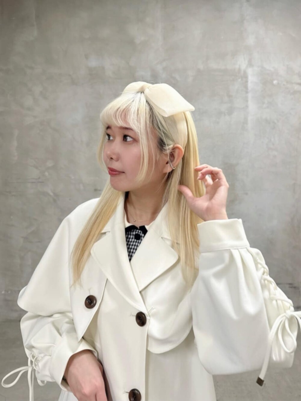 ホワイト系のトレンチコート、グリーン系のハンドバッグ、ブラック系のパンプスを着用したレディースの春コーディネートの2枚目の写真