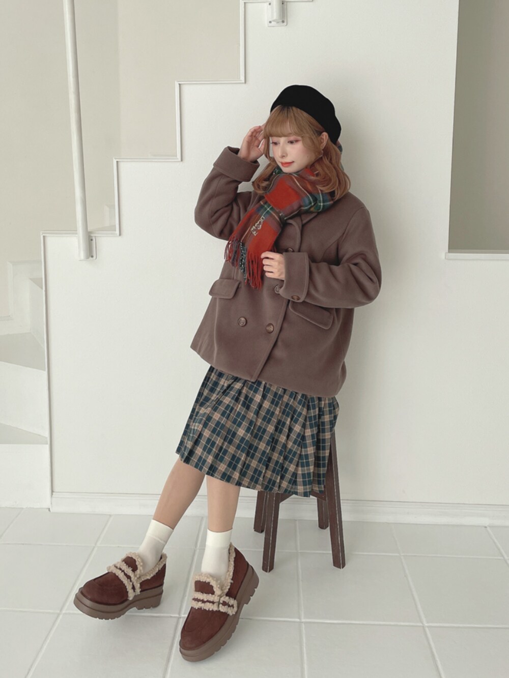 ブラウン系のモカシン/デッキシューズ、グリーン系のスカート、ブラウン系のピーコートを着用したレディースの秋コーディネートの3枚目の写真