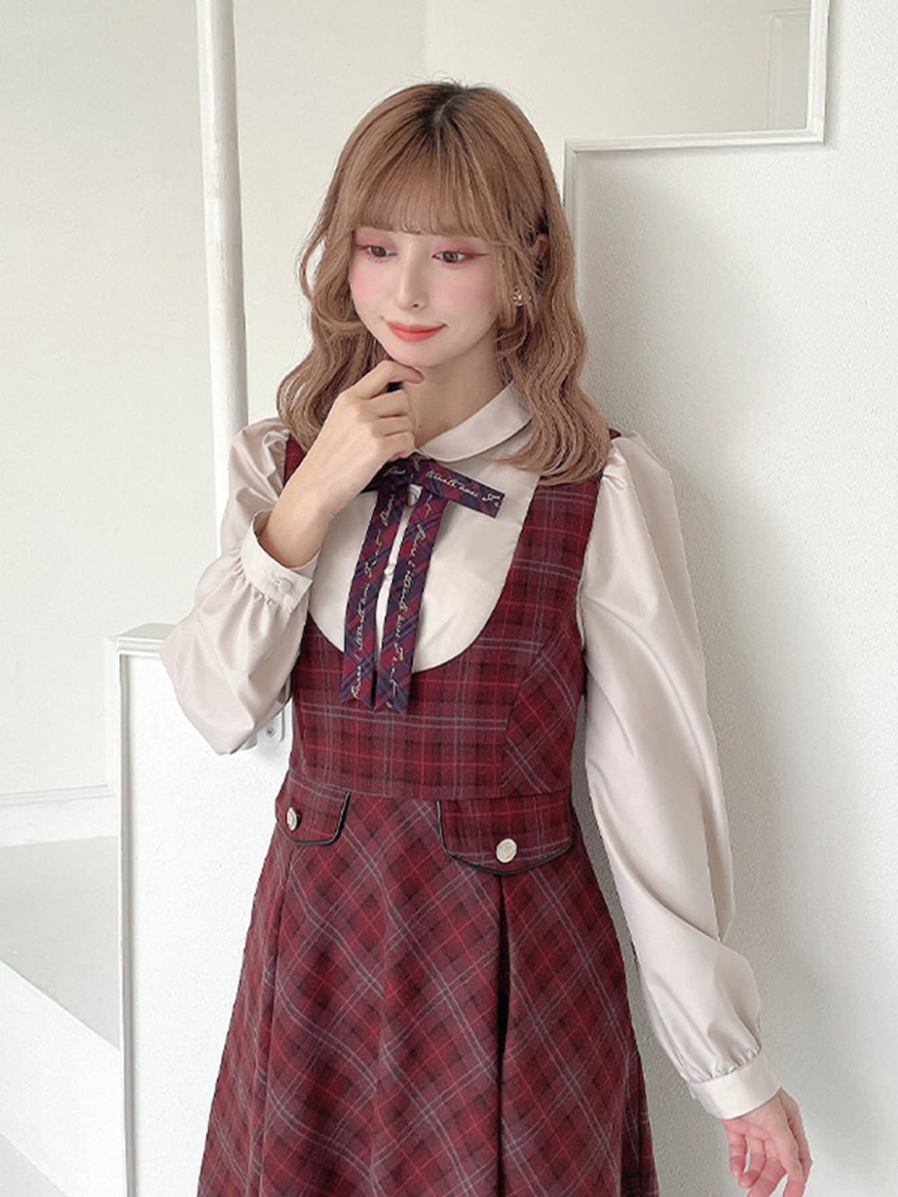 レッド系のジャンパースカート、ブラウン系のバレエシューズ、ベージュ系のシャツ/ブラウスを着用したレディースの冬コーディネートの3枚目の写真
