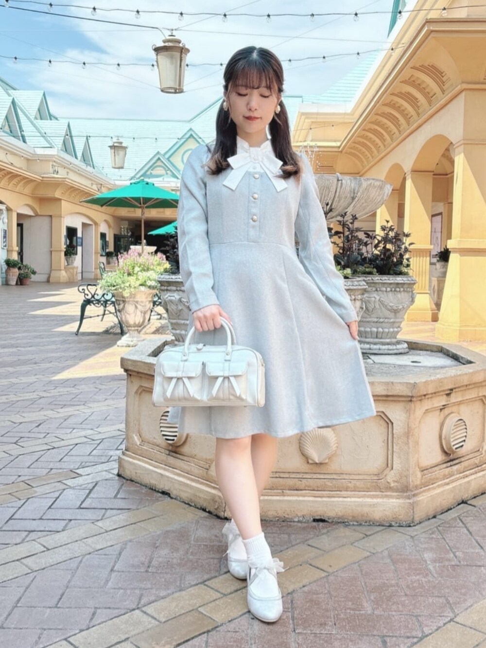 シルバー系のハンドバッグ、シルバー系のパンプス、グレー系のワンピースを着用したレディースの秋コーディネートの2枚目の写真