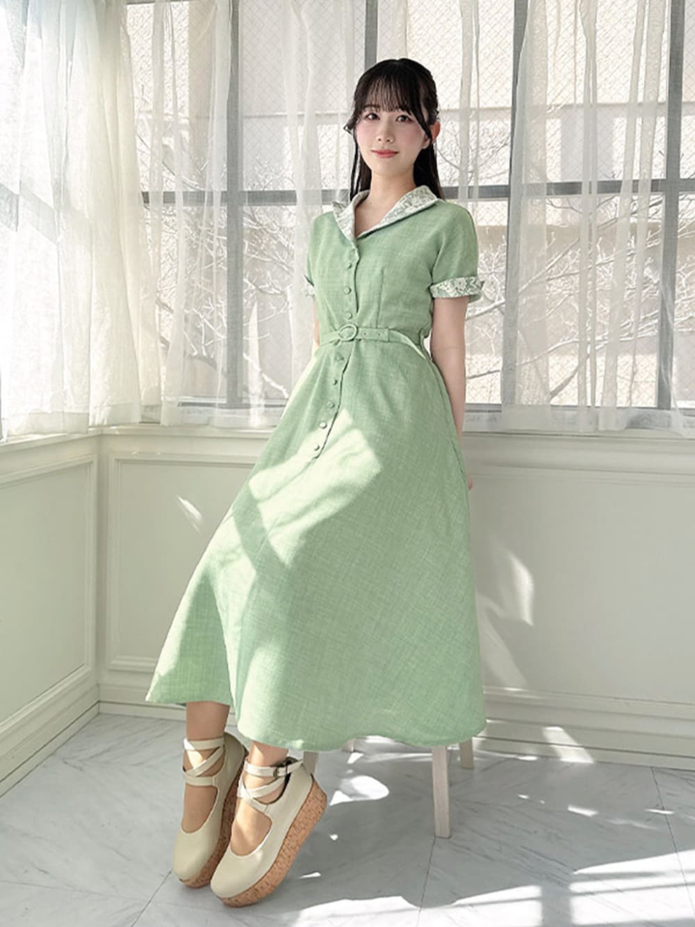 ホワイト系のパンプス、グリーン系のワンピース、ホワイト系のカーディガン/ボレロを着用したレディースの春コーディネートの2枚目の写真