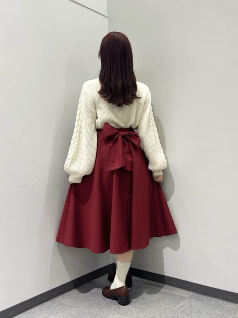 ブラウン系のローファー、レッド系のスカート、ホワイト系のニット/セーターを着用したレディースの秋コーディネートの3枚目の写真