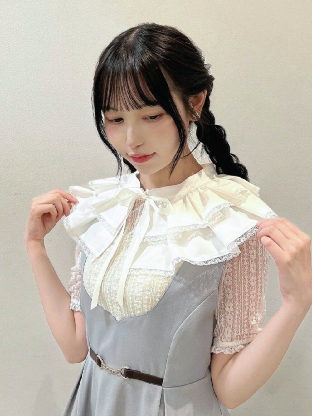 ブラウン系のパンプス、グレー系のジャンパースカート、ホワイト系の付け襟を着用したレディースの春コーディネートの2枚目の写真