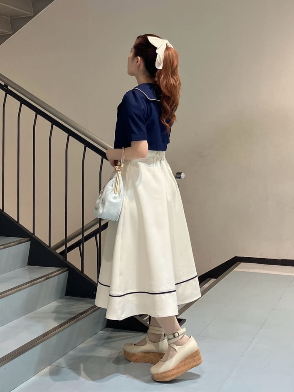 ホワイト系のパンプス、レッド系のハンドバッグ、ブルー系のジャンパースカートを着用したレディースの夏コーディネートの2枚目の写真