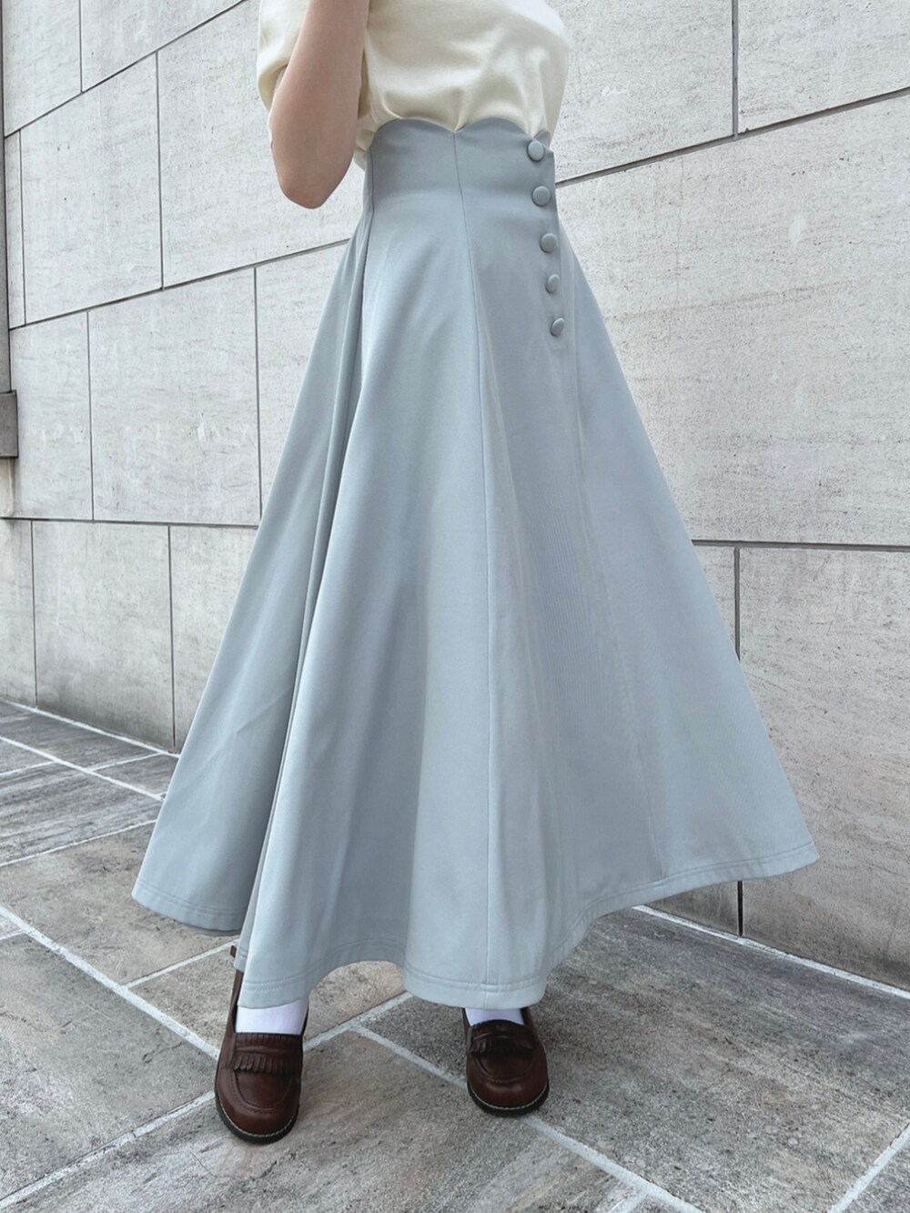 ブラウン系のローファー、グリーン系のスカート、ホワイト系のポロシャツを着用したレディースの春コーディネートの4枚目の写真