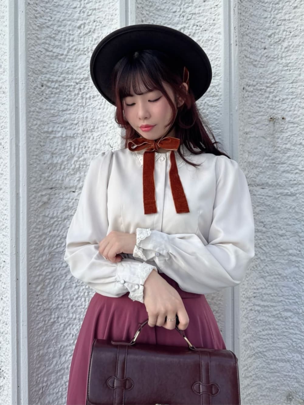 ピンク系のスカート、ブラウン系のショルダーバッグ、ブラウン系のパンプスを着用したレディースの秋コーディネートの3枚目の写真