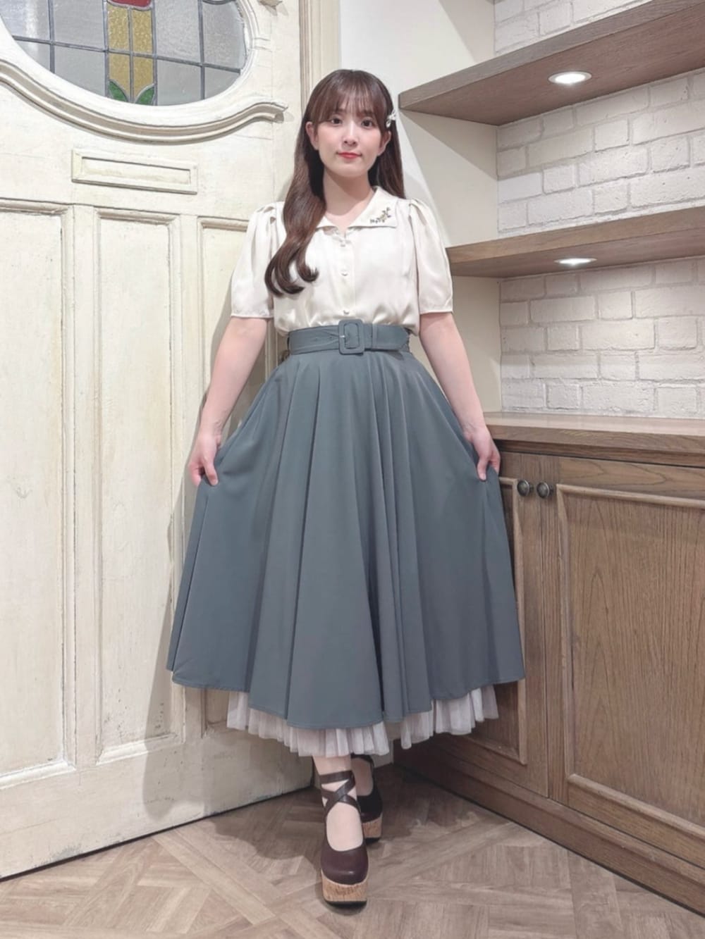 グリーン系のスカート、ブラウン系のパンプス、ベージュ系のシャツ/ブラウスを着用したレディースの秋コーディネートの2枚目の写真