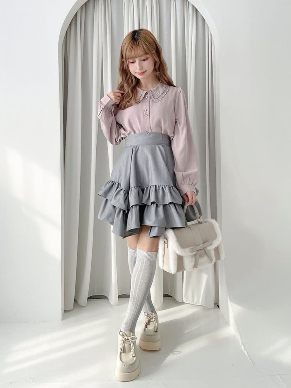 ベージュ系のハンドバッグ、グレー系のスカート、ホワイト系のモカシン/デッキシューズを着用したレディースの秋コーディネートの2枚目の写真