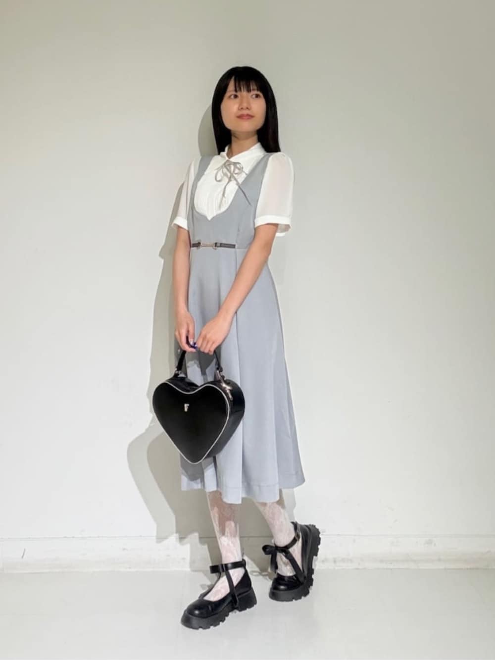 ブラック系のパンプス、ブラック系のハンドバッグ、ホワイト系のシャツ/ブラウスを着用したレディースの夏コーディネートの2枚目の写真