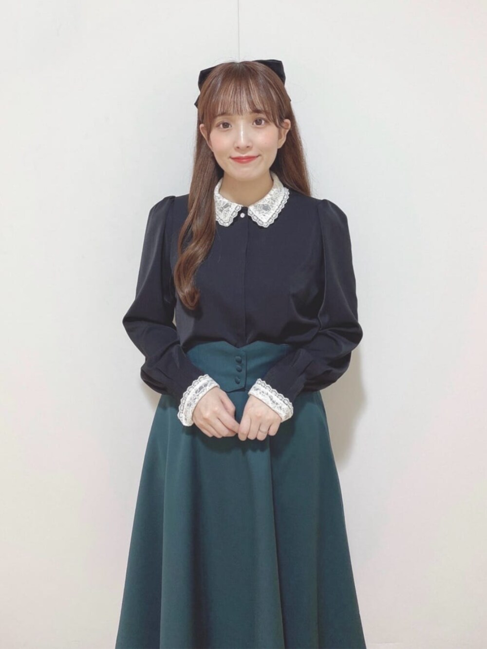 ブルー系のハンドバッグ、ブルー系のパンプス、グリーン系のスカートを着用したレディースの秋コーディネートの3枚目の写真