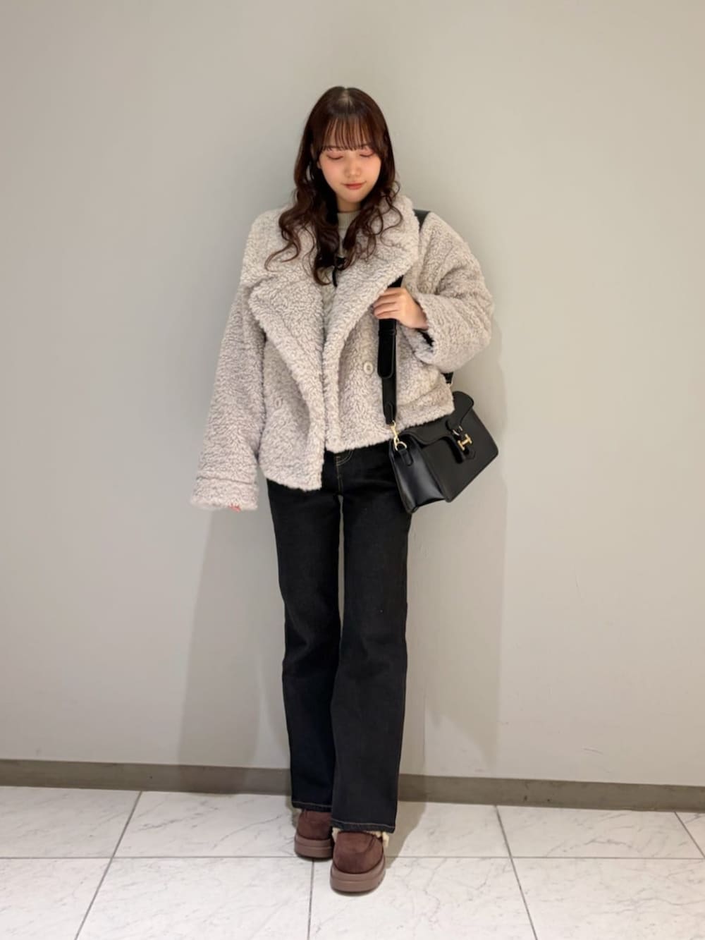 ブラック系のハンドバッグ、ブラウン系のモカシン/デッキシューズ、ブラック系のデニムパンツを着用したレディースの冬コーディネートの2枚目の写真