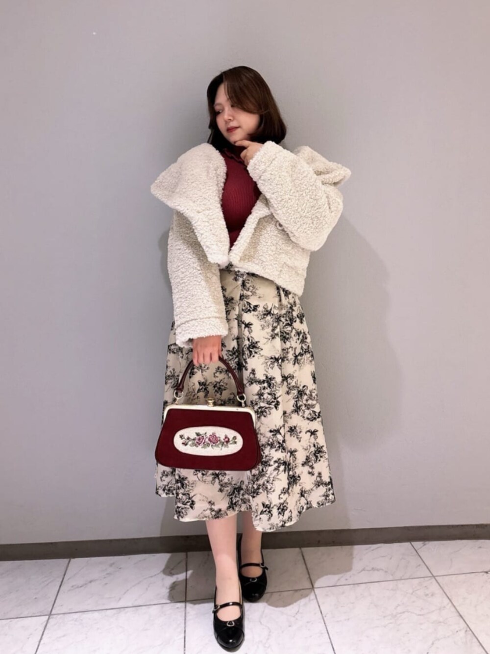 レッド系のハンドバッグ、ブラック系のパンプス、ホワイト系のその他アウターを着用したレディースの秋コーディネートの2枚目の写真