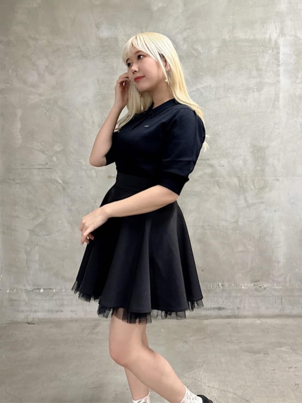 ブラック系のスカート、ブラック系のポロシャツを着用したレディースの春コーディネートの2枚目の写真