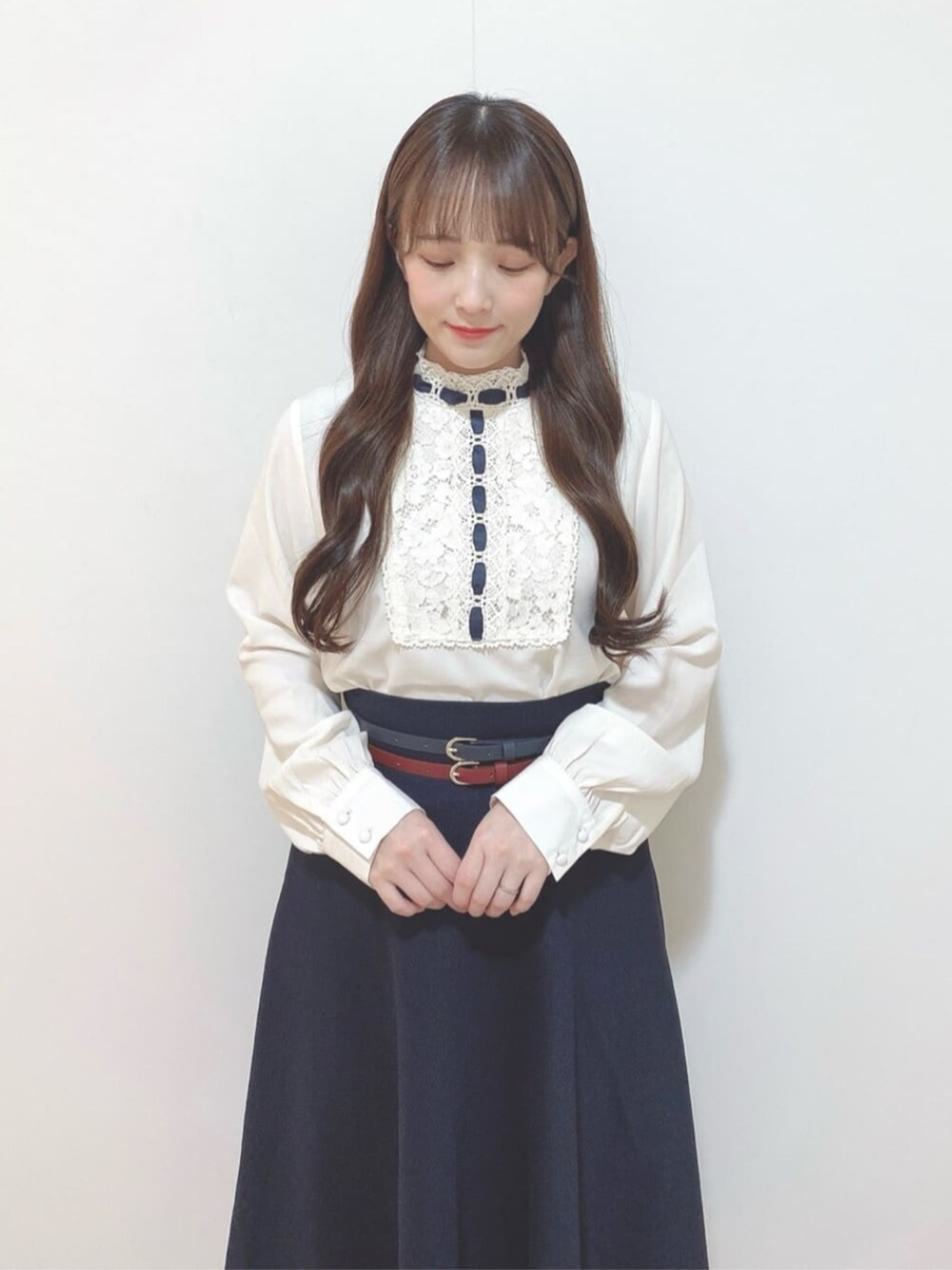 ブルー系のスカート、ホワイト系のハンドバッグ、ホワイト系のパンプスを着用したレディースの春コーディネートの2枚目の写真