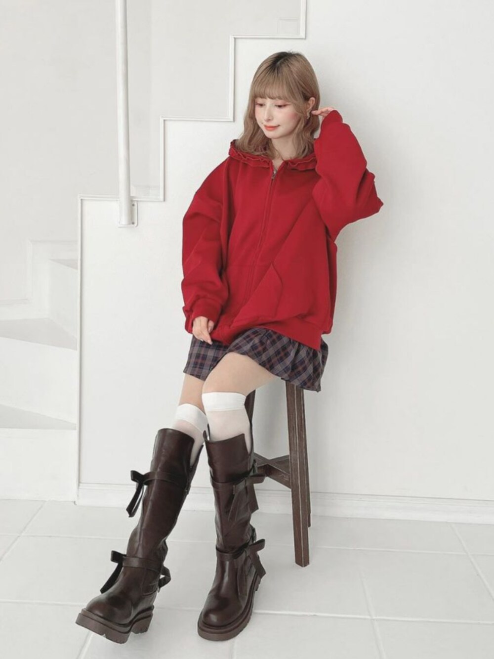 ブラウン系のブーツ、レッド系のパーカー、ブルー系のスカートを着用したレディースの秋コーディネートの2枚目の写真