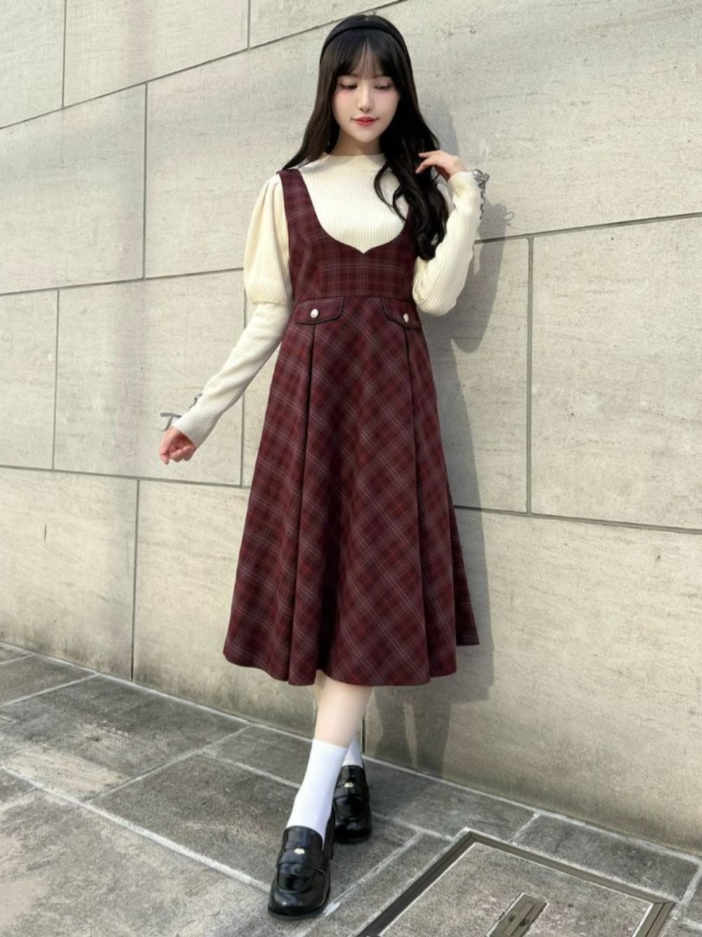 ブラック系のローファー、ホワイト系のニット/セーター、レッド系のジャンパースカートを着用したレディースの秋コーディネートの2枚目の写真