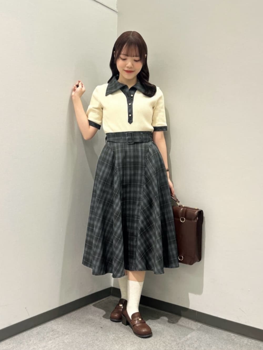 ブラウン系のローファー、ブラウン系のハンドバッグ、グリーン系のスカートを着用したレディースの春コーディネートの2枚目の写真