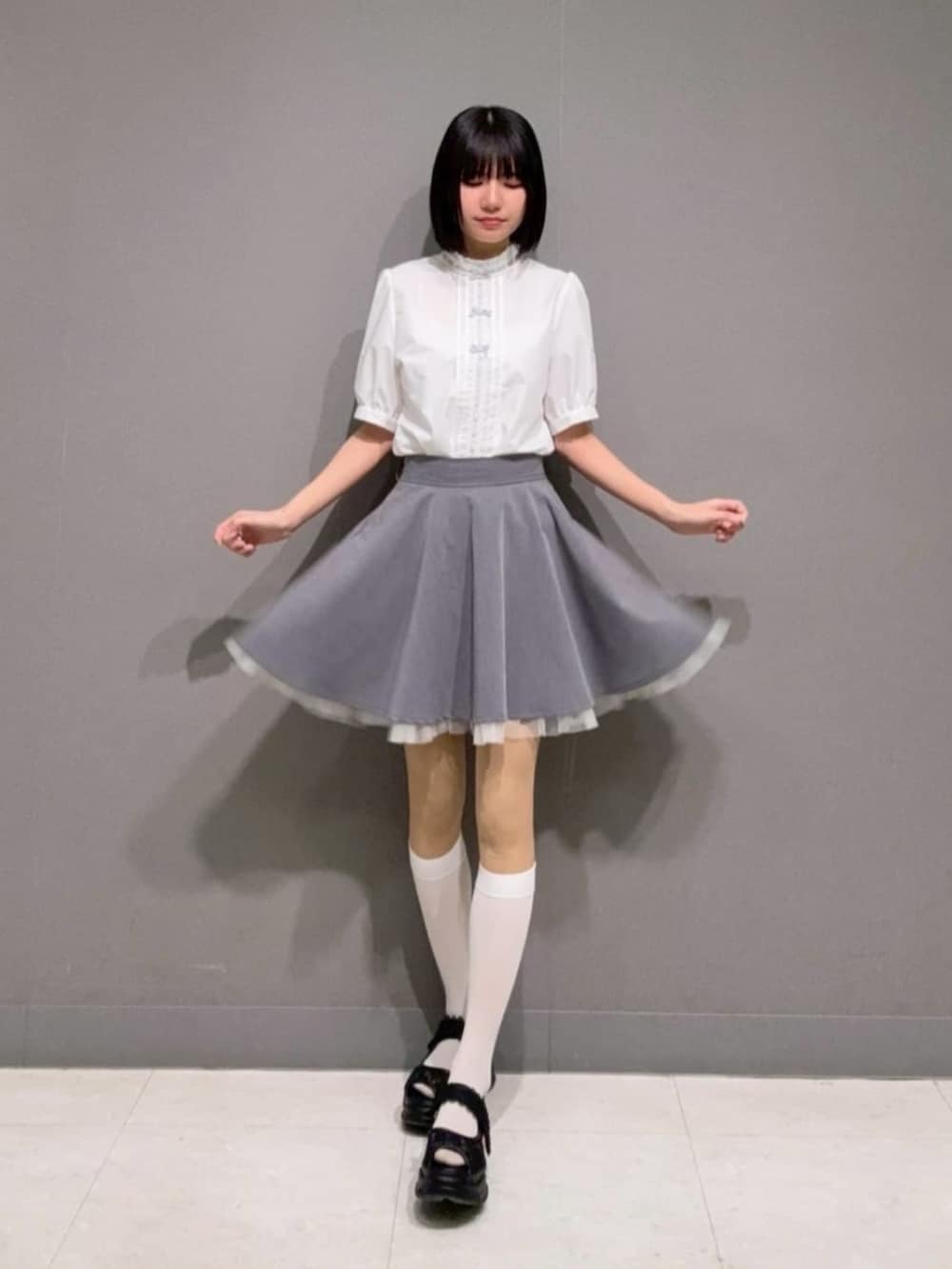 グレー系のスカート、ホワイト系のシャツ/ブラウス、ブラック系のサンダルを着用したレディースの春コーディネートの3枚目の写真