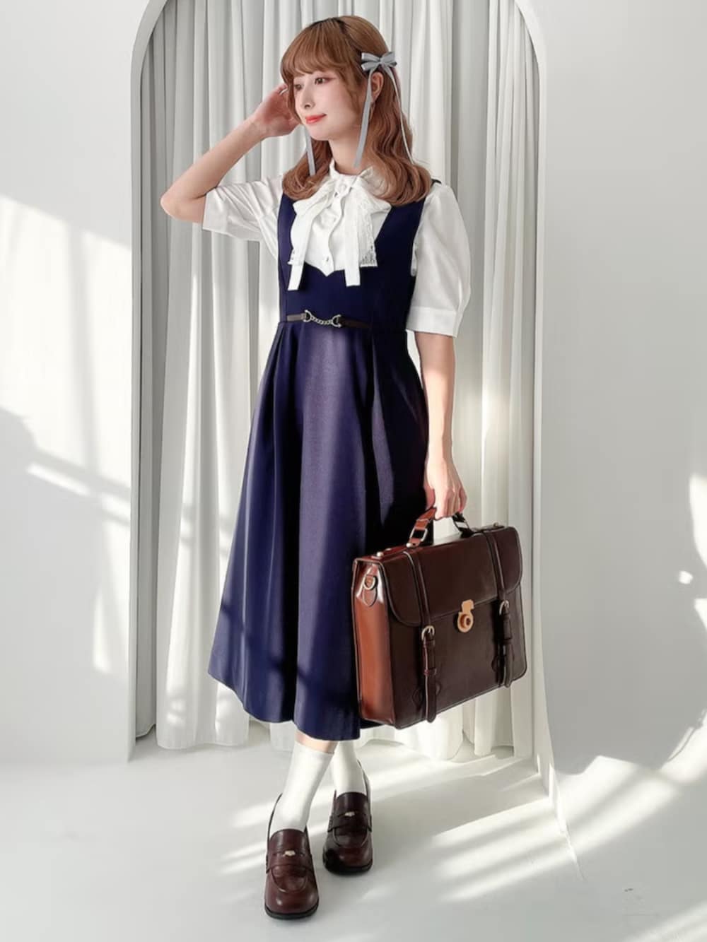 ブラック系のローファー、ホワイト系のシャツ/ブラウス、ブルー系のジャンパースカートを着用したレディースの春コーディネートの2枚目の写真