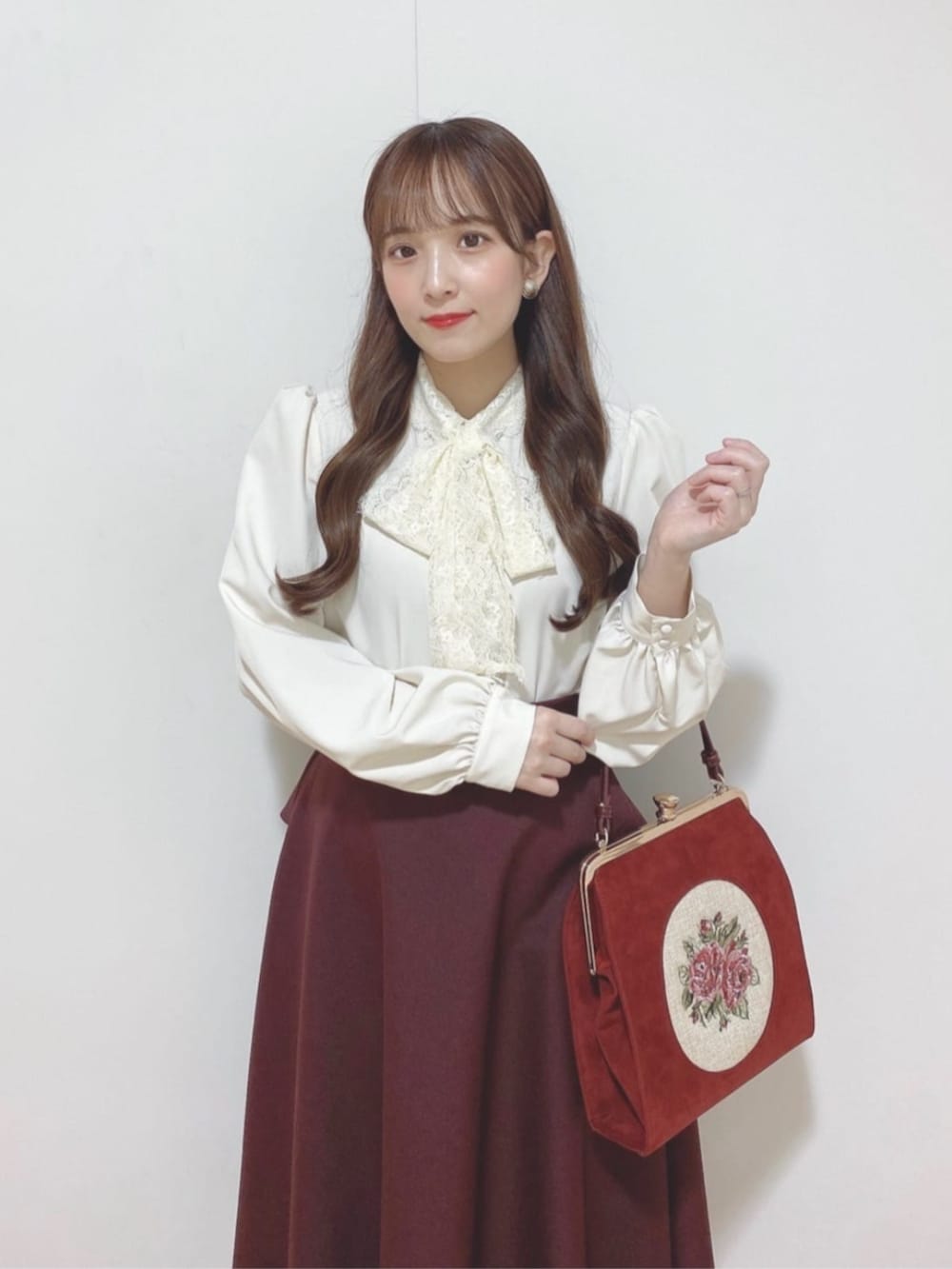 レッド系のパンプス、レッド系のハンドバッグ、ホワイト系のシャツ/ブラウスを着用したレディースの秋コーディネートの2枚目の写真