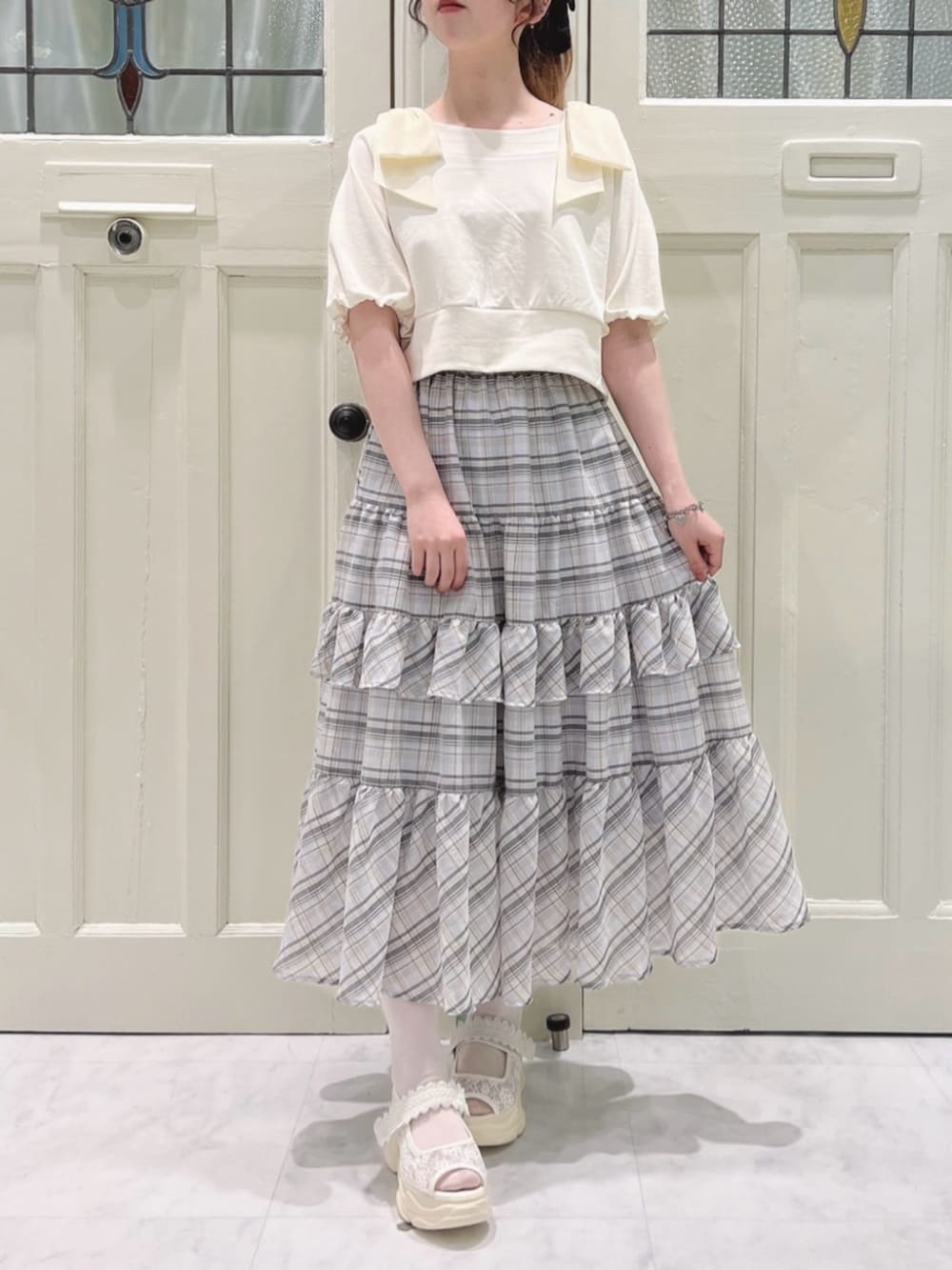 ホワイト系のサンダル、ホワイト系のスカート、ホワイト系のTシャツ/カットソーを着用したレディースの春コーディネートの2枚目の写真