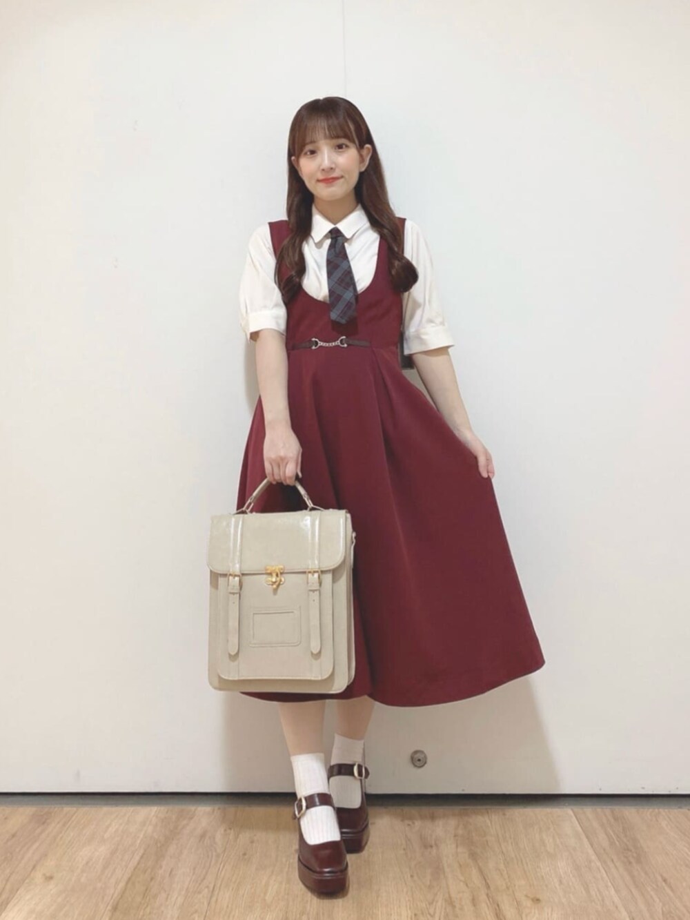 ベージュ系のハンドバッグ、ブラウン系のパンプス、レッド系のジャンパースカートを着用したレディースの夏コーディネートの2枚目の写真
