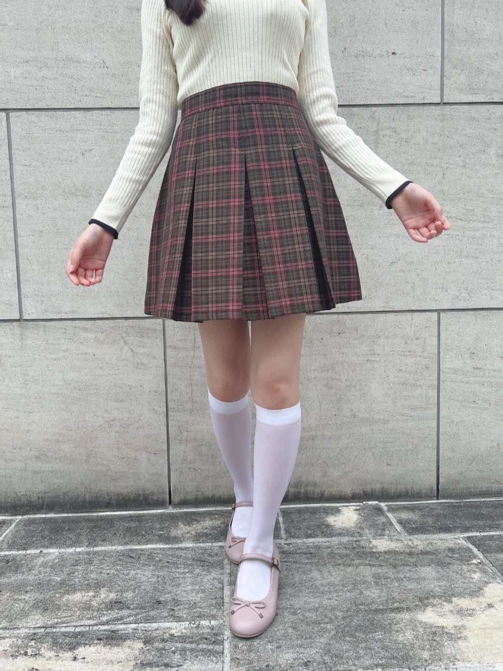 グリーン系のスカート、ホワイト系のニット/セーター、ピンク系のパンプスを着用したレディースの秋コーディネートの2枚目の写真