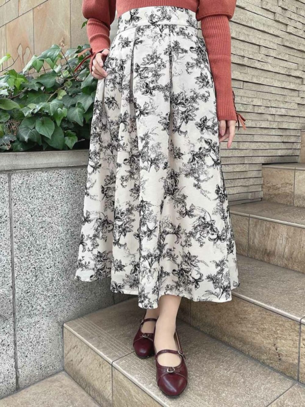 レッド系のパンプス、オレンジ系のニット/セーター、ホワイト系のスカートを着用したレディースの冬コーディネートの2枚目の写真