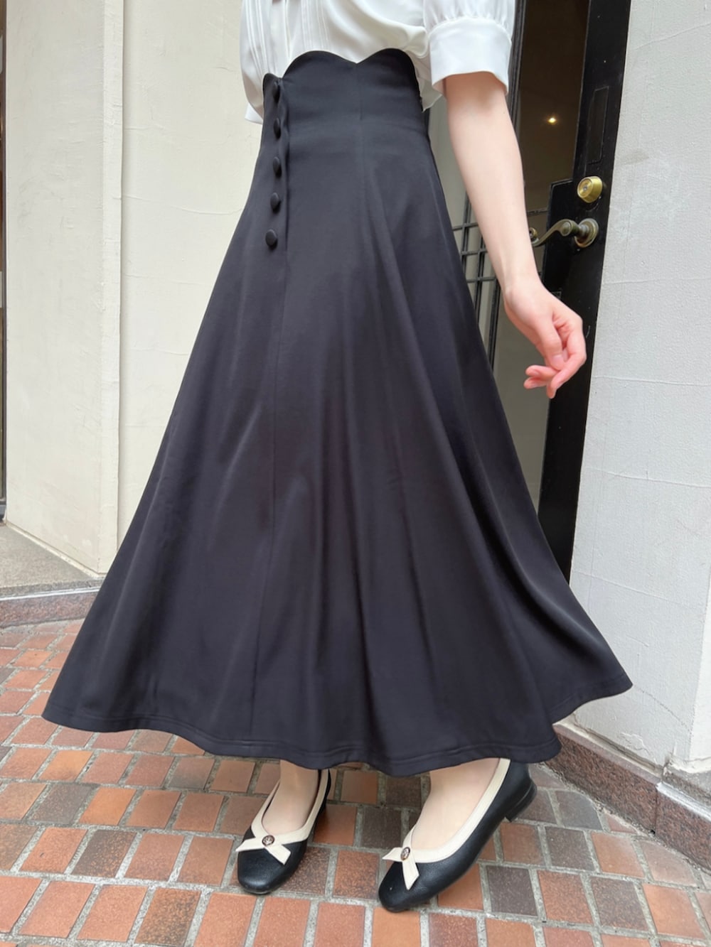 ブラック系のパンプス、ホワイト系のシャツ/ブラウス、ブラック系のスカートを着用したレディースの春コーディネートの2枚目の写真