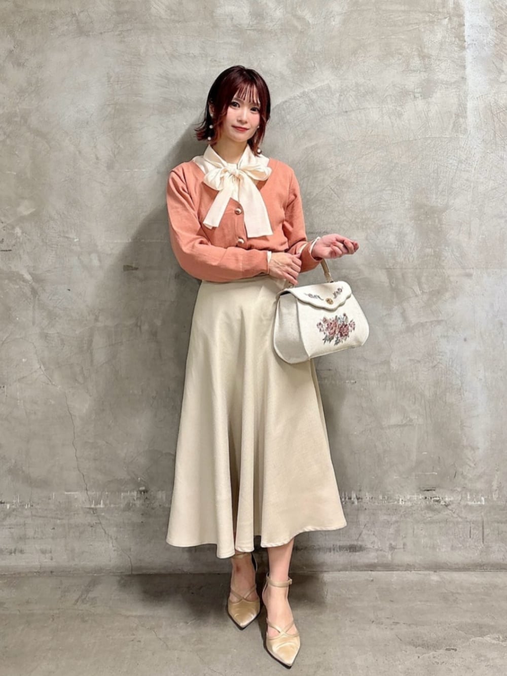 ピンク系のシャツ/ブラウス、ホワイト系のハンドバッグ、ベージュ系のスカートを着用したレディースの冬コーディネートの2枚目の写真