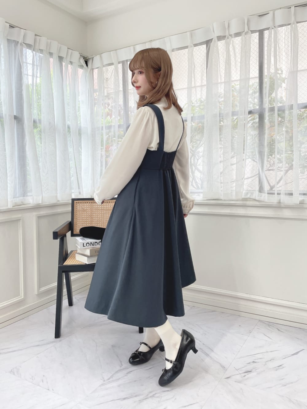 ブラック系のパンプス、グレー系のジャンパースカート、ホワイト系のシャツ/ブラウスを着用したレディースの秋コーディネートの2枚目の写真