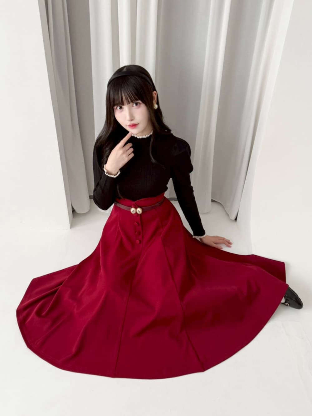 ブラック系のパンプス、ブラック系のニット/セーター、レッド系のスカートを着用したレディースの冬コーディネートの2枚目の写真