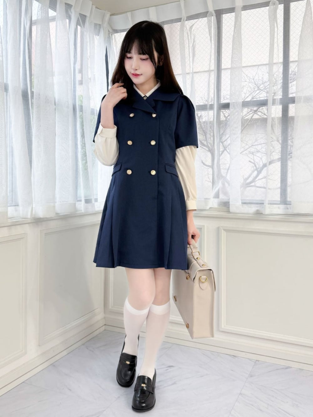 ブラック系のローファー、ホワイト系のハンドバッグ、ブルー系のワンピースを着用したレディースの春コーディネートの2枚目の写真